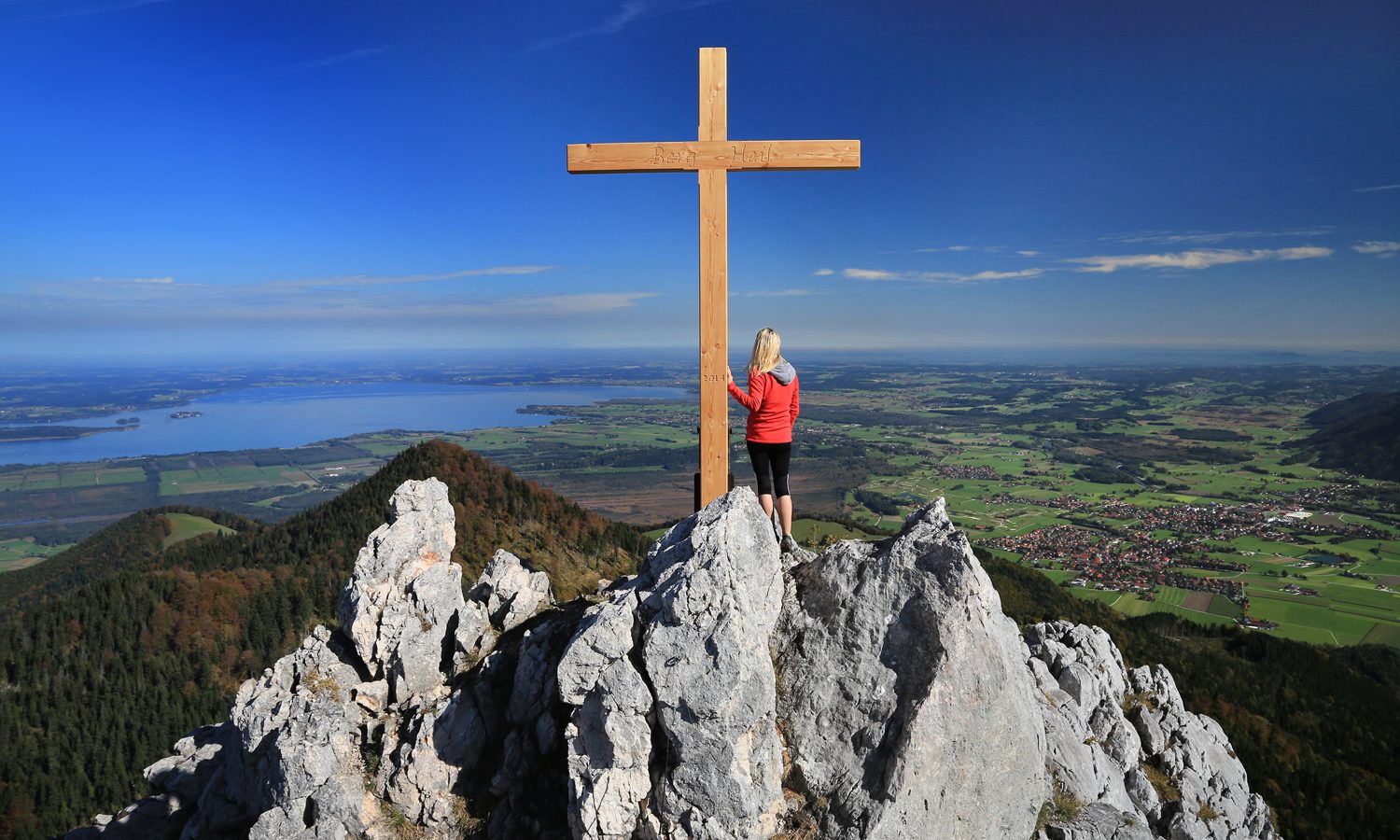 Andrea Wittmann am Gipfelkreuz „Berg Heil“, Blick über den Chiemsee und das Alpenvorland