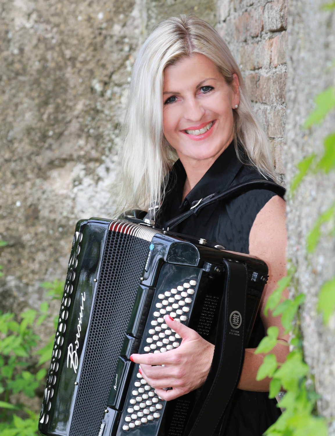 Andrea Wittmann with her accordion in front of an old stone wall
