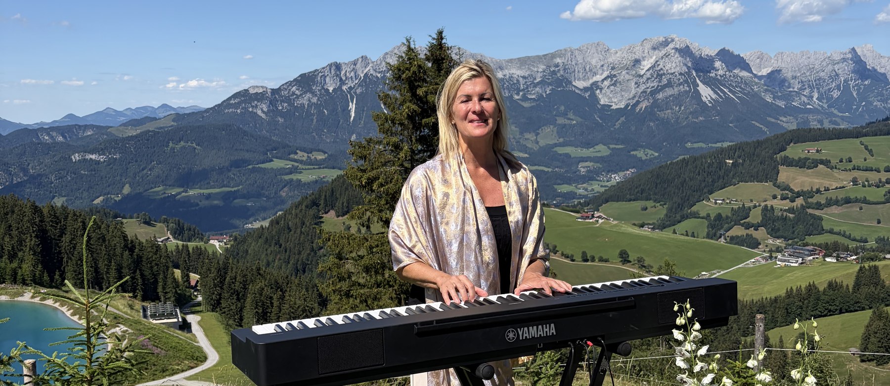 Andrea Wittmann spielt E-Piano bei einer Trauung auf einer Bergwiese, dahinter der Wilde Kaiser
